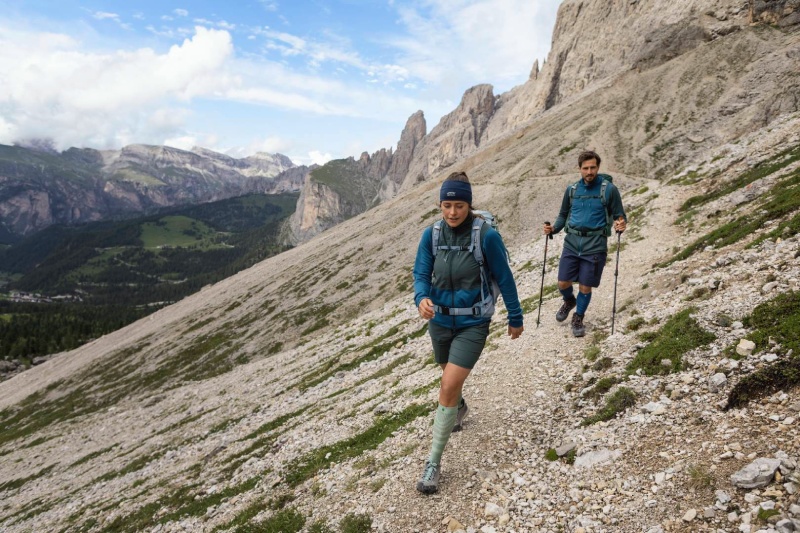 Una donna e un uomo escursione su una catena montuosa circondata da rocce e indossano bastoncini telescopici dello zaino e calzini da escursioni lunghi