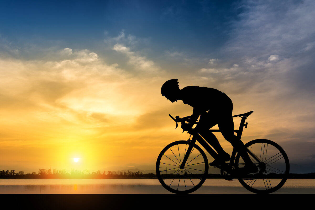Silhouette di un ciclista all'ombra al tramonto