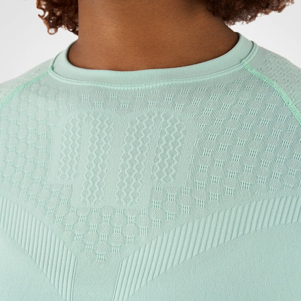 Primo piano di una maglia a compressione verde menta con tessuto strutturato, che mette in evidenza la consistenza e i dettagli del materiale.