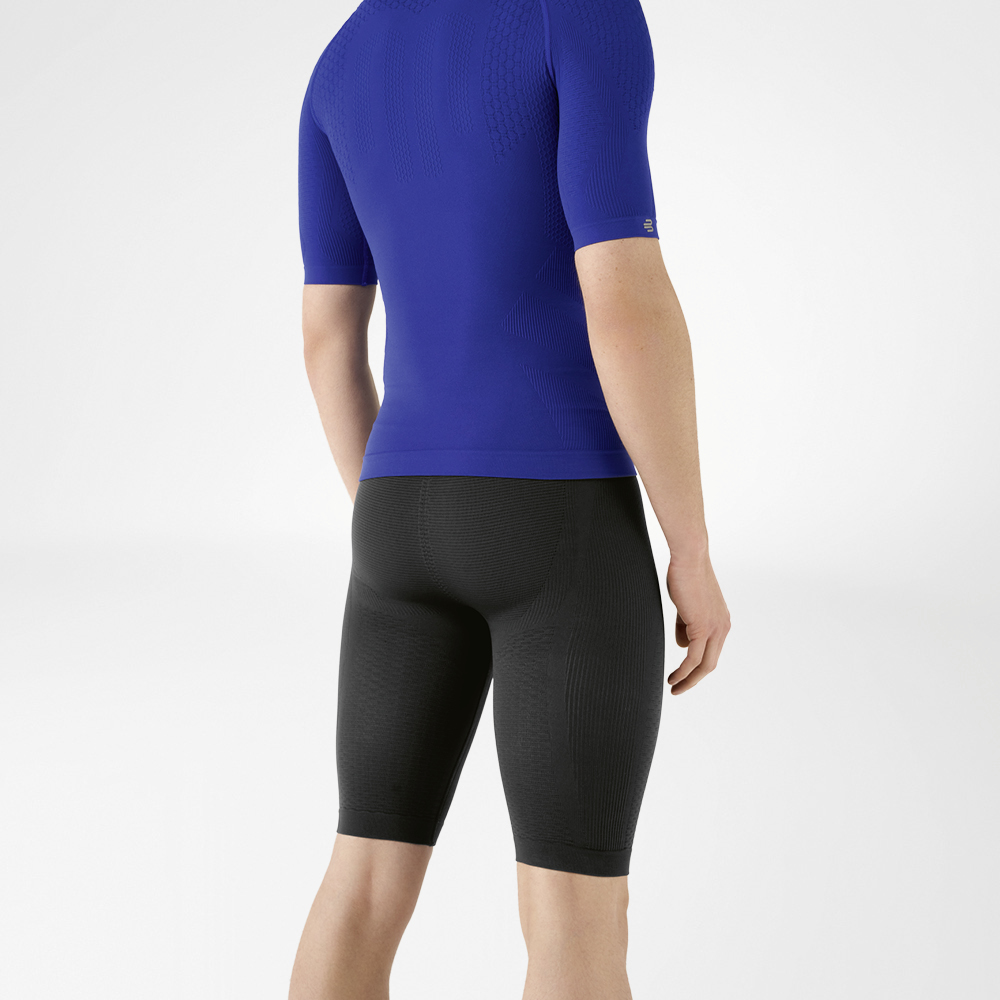 L'uomo indossa una camicia blu aderente che mette in risalto la parte superiore del corpo e pantaloni sportivi aderenti blu navy lunghi fino al ginocchio che abbracciano la parte inferiore del corpo.