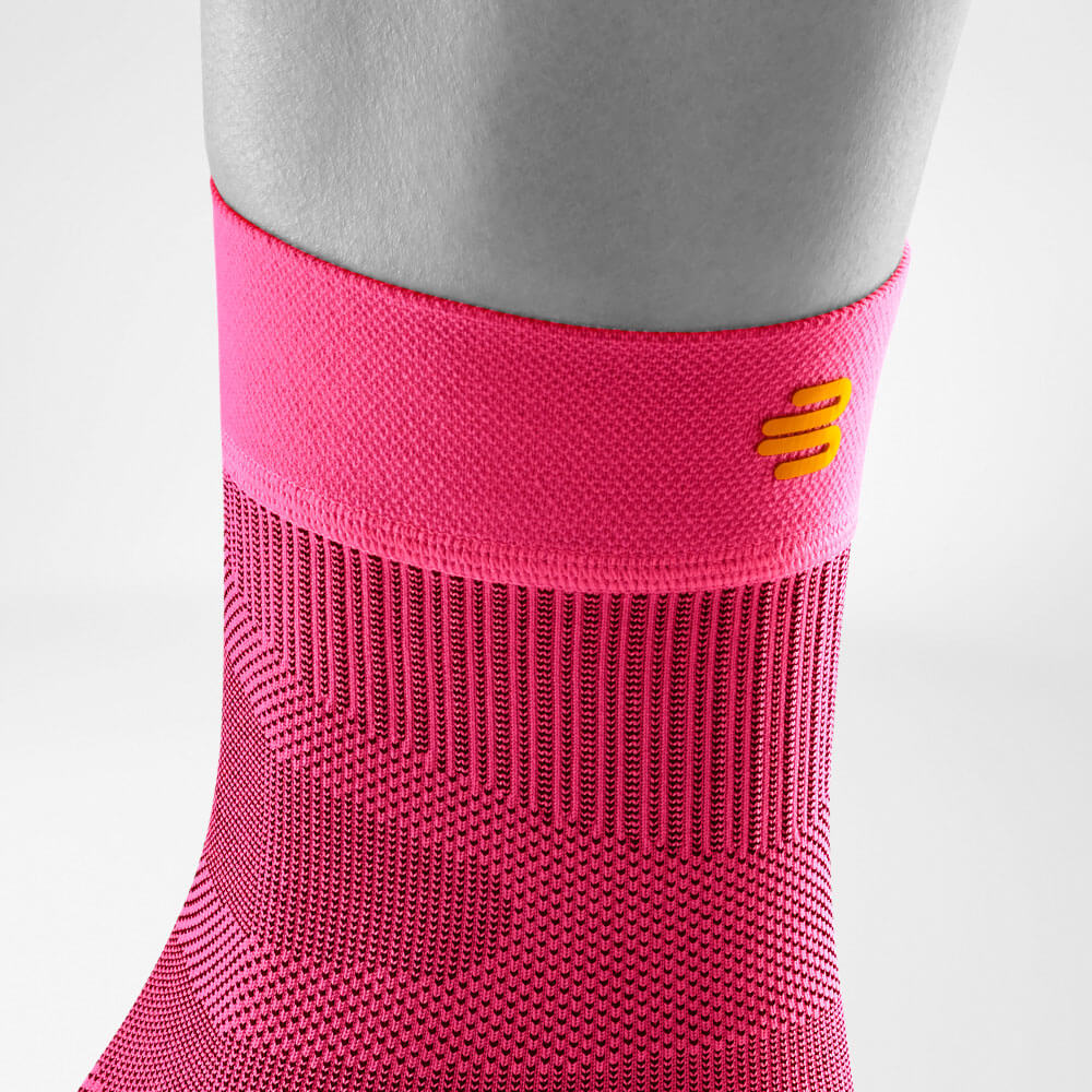 Vista dettagliata dell'area superiore delle Sportsleeves di colore rosa per la caviglia tra cui un percorso a maglia e logo