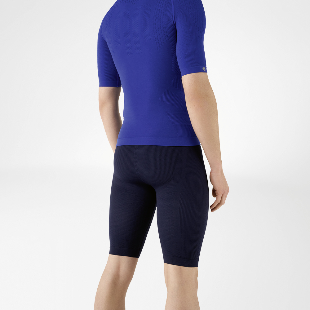L'uomo indossa una camicia blu aderente che mette in risalto la parte superiore del corpo e pantaloni sportivi aderenti blu navy lunghi fino al ginocchio che abbracciano la parte inferiore del corpo.
