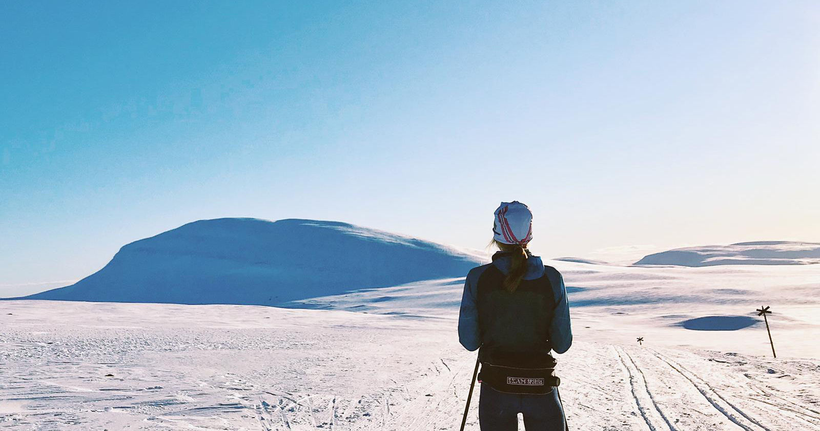 Ski Ranner guarda in lontananza in un ampio paesaggio invernale coperto di neve senza alberi in un cielo blu