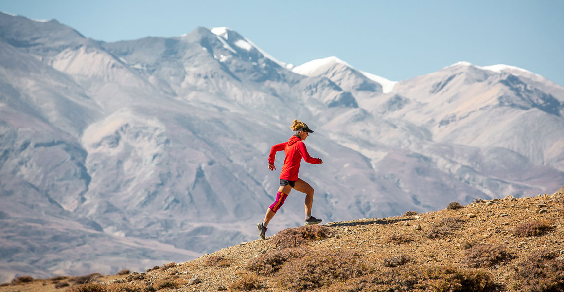 Trekking in Nepal - un panorama che non potrebbe essere più impressionante Trailläriner corre con l'Himalaya sullo sfondo e indossa un tandage del ginocchio