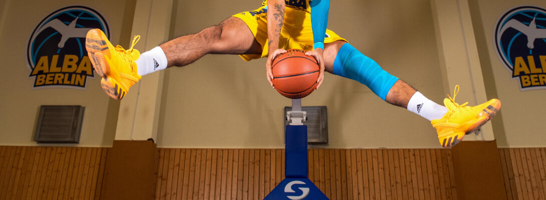 I giocatori di basket fanno un atto di bilanciamento, indossa una manica al ginocchio sulla gamba sinistra