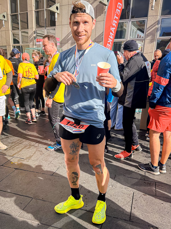 Al traguardo della mezza maratona di Halle, orgoglioso con medaglia e bevanda In piedi orgoglioso al traguardo dopo aver completato la mezza maratona di Halle, con una medaglia e una bevanda in mano, assaporando il momento dopo la gara.