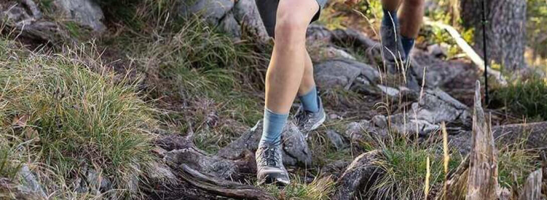 Calzini da escursioni merino di media lunghezza durante le escursioni nella foresta La donna errante su una superficie pietrosa indossa calzini escursionistici di media lunghezza