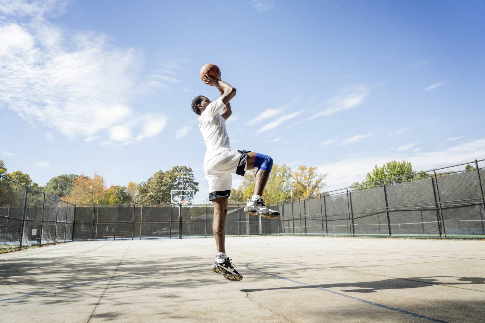 Cruciale per ogni tiro riuscito: determinazione e precisione I giocatori di basket saltano su un campo di strada per il tiro dalle mani con la palla sopra la testa, piegati nell'altro, mostrano l'altro verticalmente verso il basso